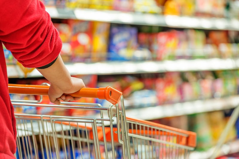 Cliente empurrando carrinho em um corredor de supermercado